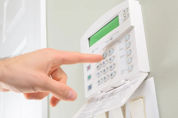 Eine Hand gibt einen Code auf einer Sicherheitsanlage ein