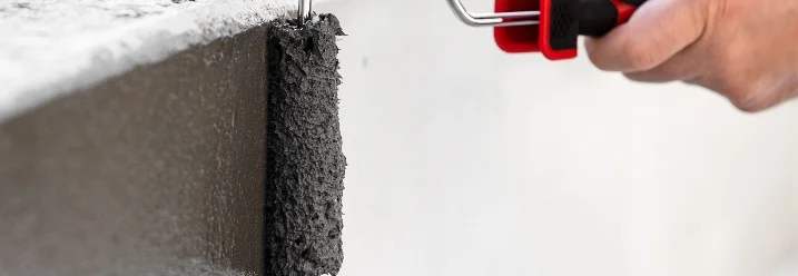 Person streicht Wand mit Farbroller