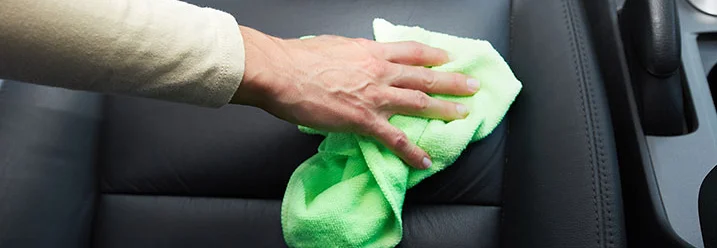 Hand reinigt Autositz mit Tuch