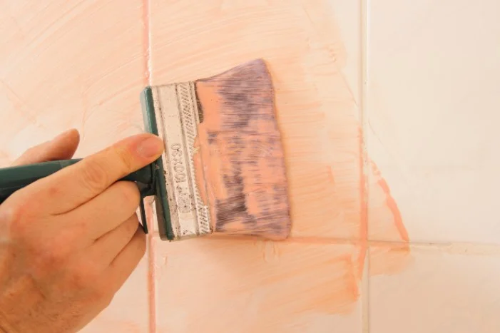 Hand trägt Farbe mit Pinsel auf
