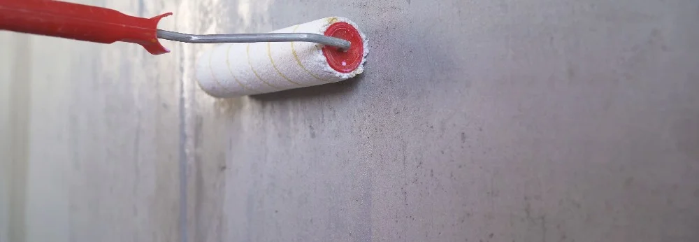 Farbrolle trägt Farbe auf Wand auf