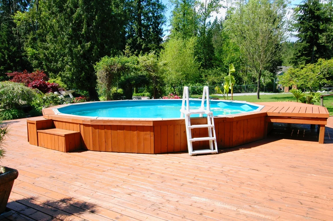 Aufstellpool mit Holzumrandung und Leiter.