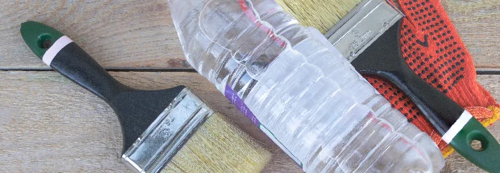 Zwei Pinsel, Arbeitshandschuhe und eine Wasserflasche