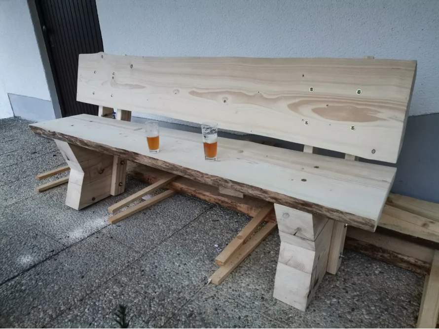 Unfertige Holzbank mit zwei Gläsern Bier darauf