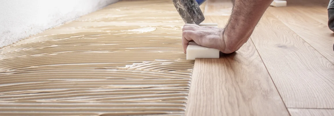 Person verlegt Holzdielen mit Hammer