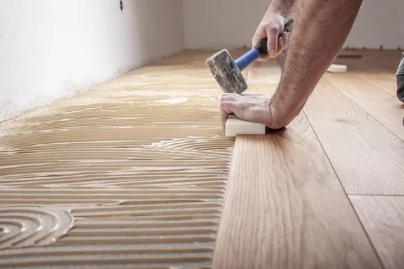 Person verlegt Holzdielen mit Hammer