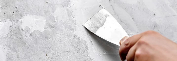 Hand spachtelt Wand mit Spachtel