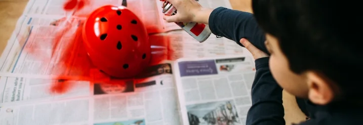 Kind lackiert Fahrradhelm mit Spraydose