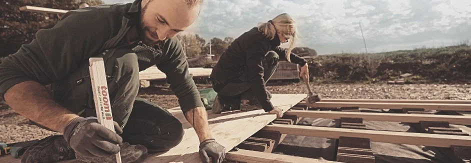 Zwei Personen bauen ein Holzgerüst