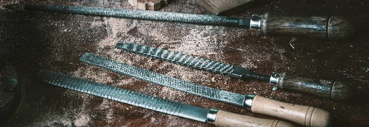 Vier Feilen auf einem Tisch mit Sägespänen