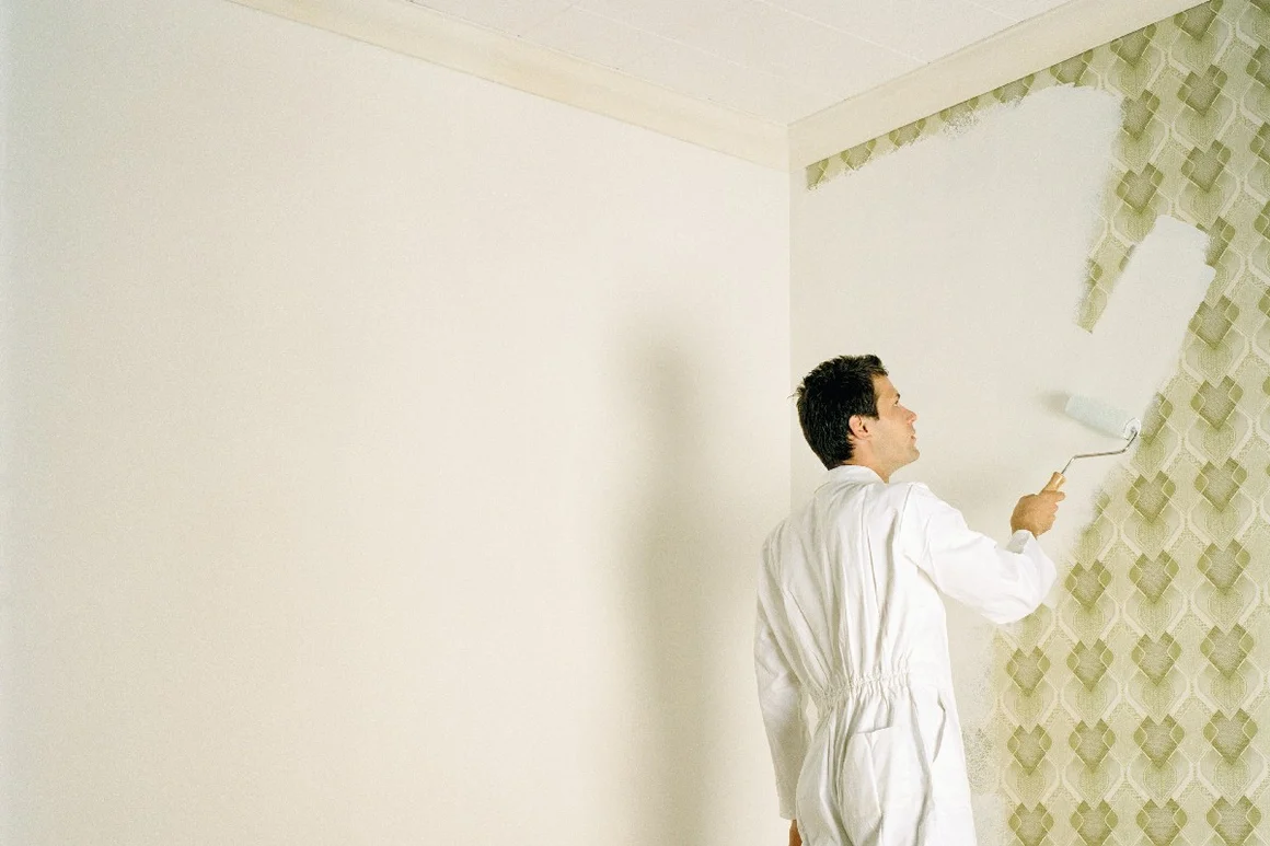 Person streicht Wand weiß