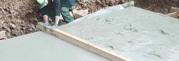 Person glättet Beton mit einer Latte