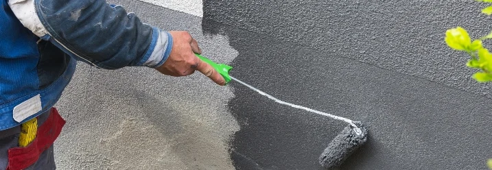 Person streicht Wand grau
