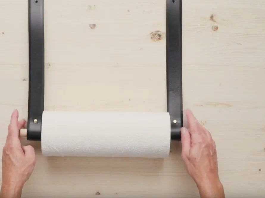 Hände befestigen Küchenrollenhalter an Wand