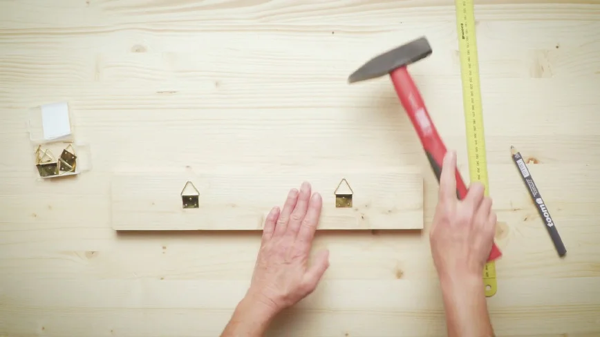 Person bringt Haken mit Hammer an