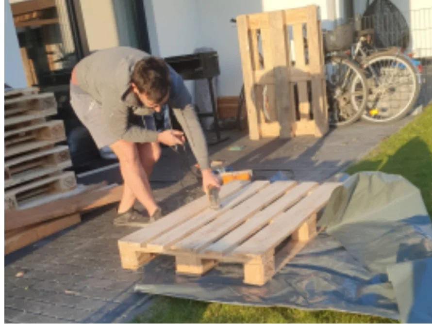 Person baut Holzpalette mit Tacker zusammen