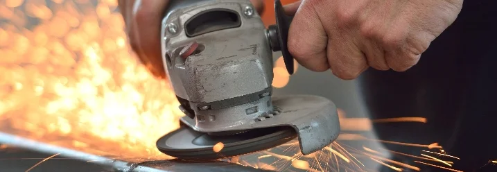 Person schneidet Metall mit einer Schleifmaschine.