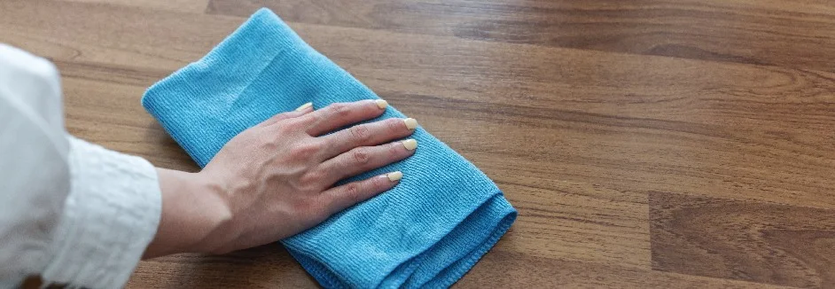 Hand reinigt Holztisch mit Tuch