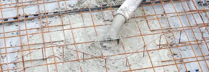 Beton wird mit einem Schlauch in ein Gitter gefüllt.