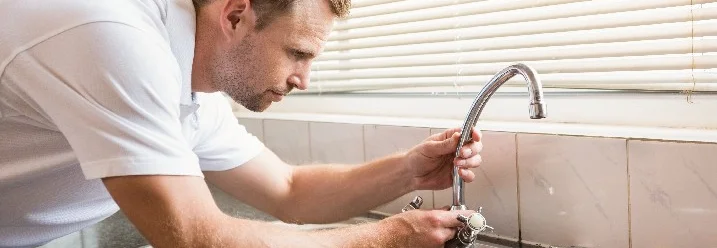 Person repariert Wasserhahn