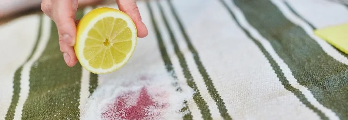 Hand träufelt Zitrone auf Fleck