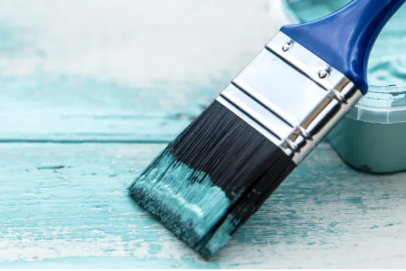 Pinsel trägt blaue Farbe auf Holz auf