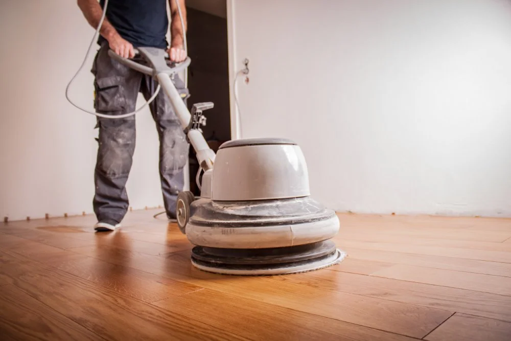 Handwerker ölt Parkettboden mit großer Poliermaschine.