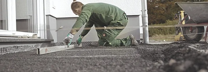 Person verwendet eine Wasserwaage auf Schotter.