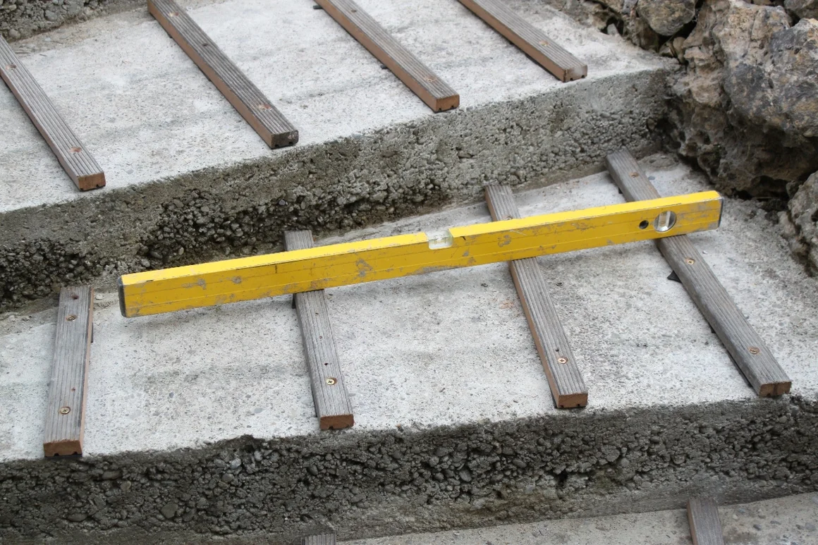 Wasserwaage auf einer Treppe aus Beton und Holz