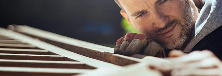 Person fährt mit Hand über Holzoberfläche