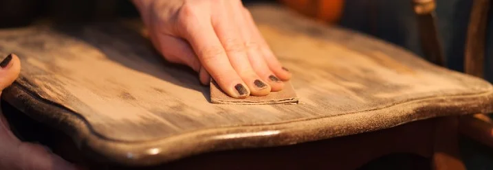 Person schleift Holztisch mit Schleifpapier