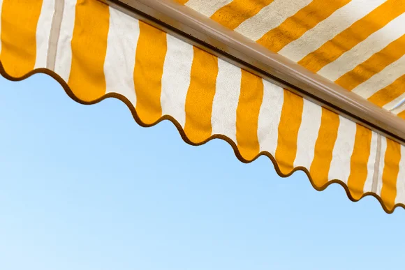 Gelb-weiße Markise vor blauem Himmel