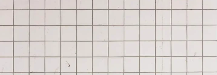 Weiße Fliesenwand mit dunklen Fugen