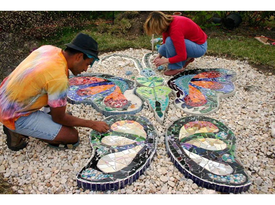 Zwei Personen legen ein Mosaik in Form eines Schmetterlings.