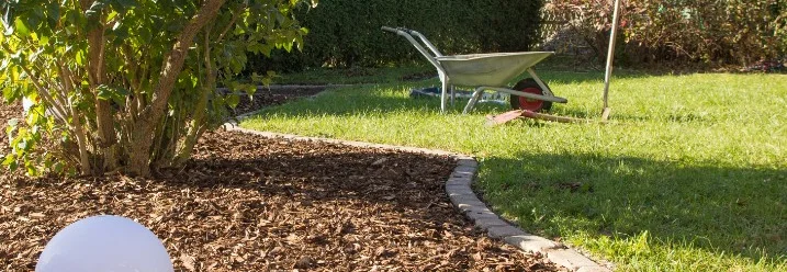 Ein Garten mit Rindenmulch, Wiese und einer Schubkarre