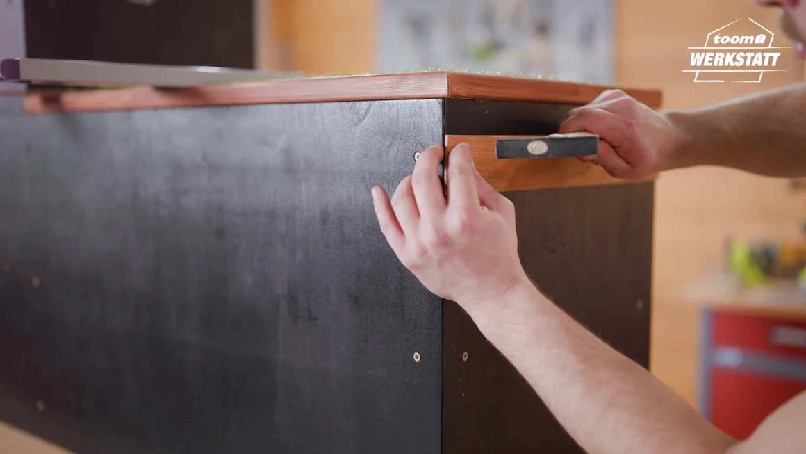 Person befestigt Holzleiste mit Hammer