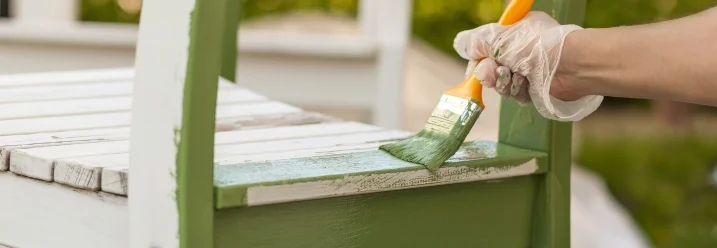 Person streicht Stuhl grün