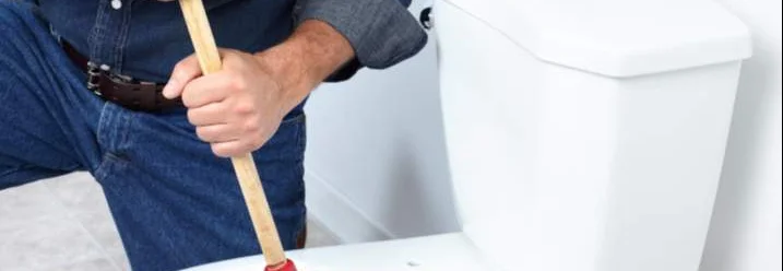 Person benutzt Pömpel in Toilette
