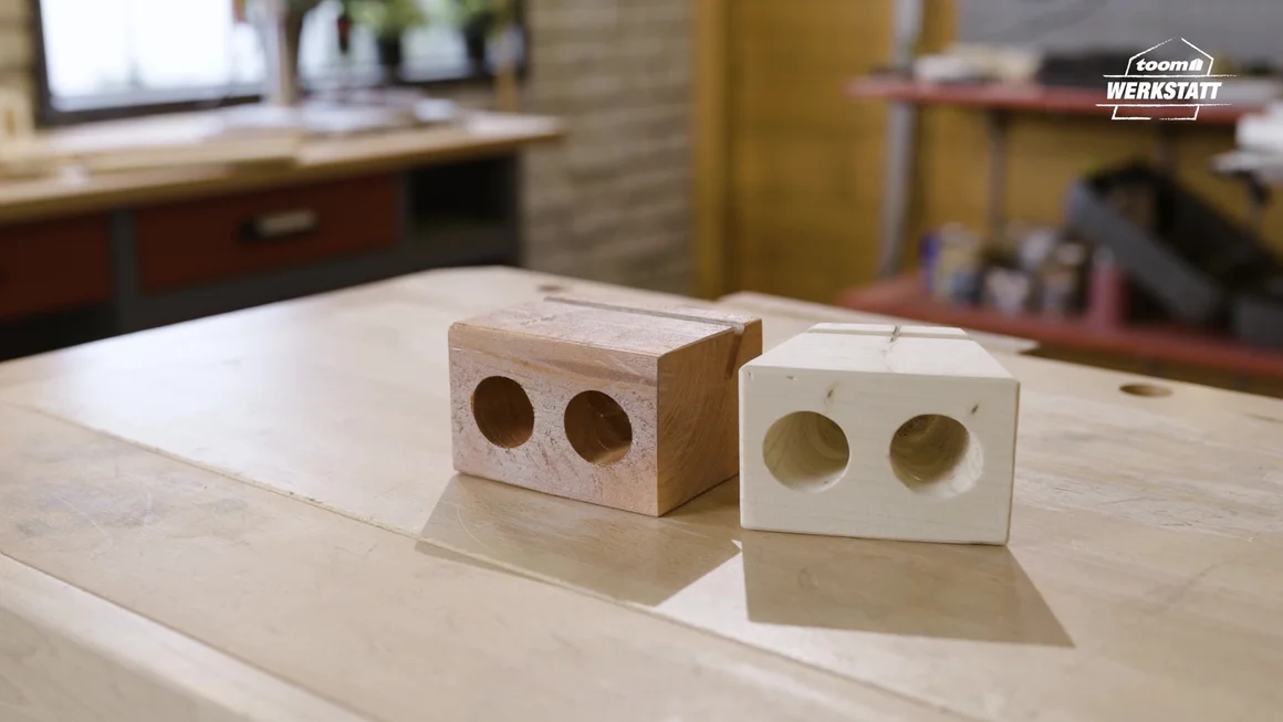 Zwei Holzstücke mit Löchern als Handyhalterung