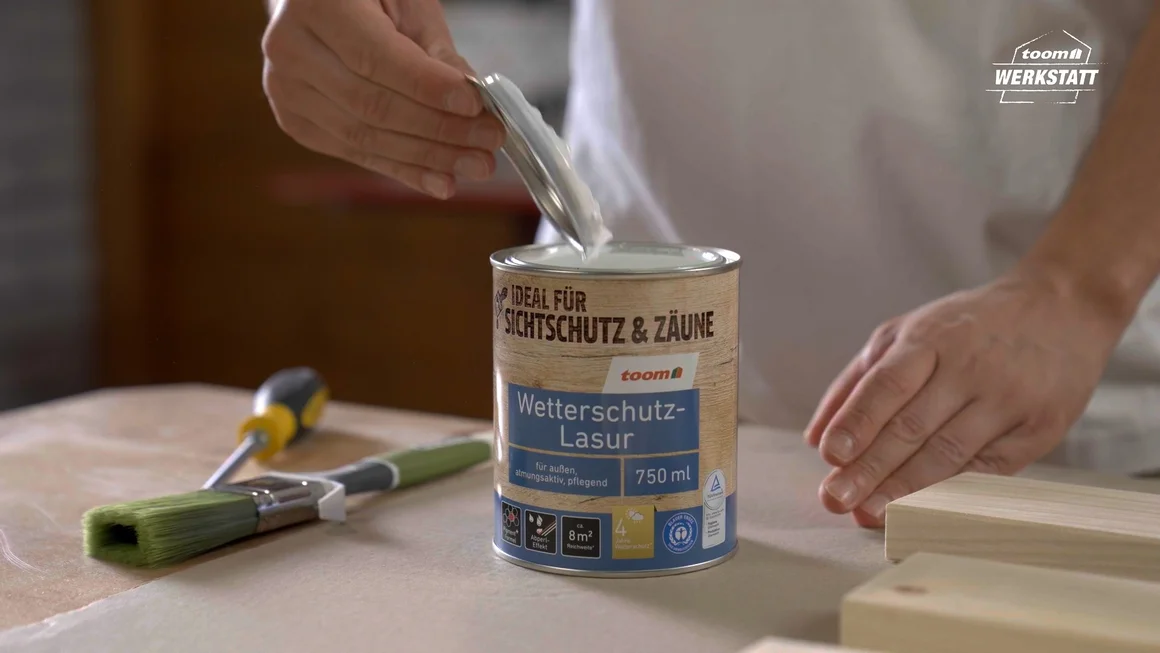 Person öffnet eine Dose mit Wetterschutzlasur