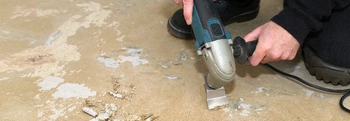 Person entfernt Bodenbelag mit Stripper.