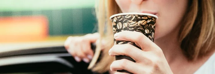 Person trinkt aus einem Kaffeebecher.