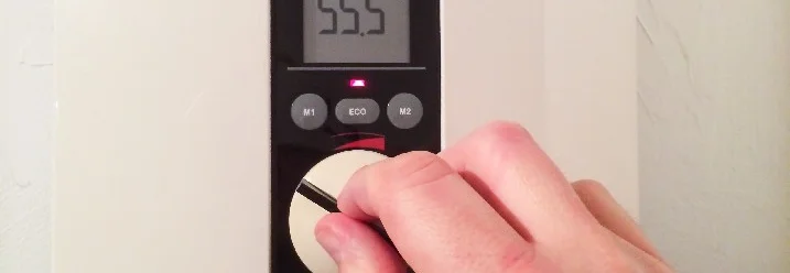 Hand stellt Temperaturregler ein