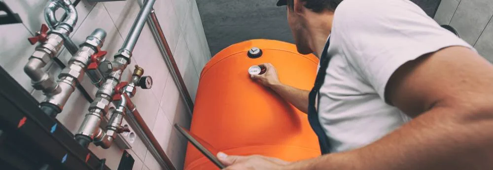 Der Techniker überprüft mit einem Tablet in der Hand die Heizungsanlage im Heizraum.