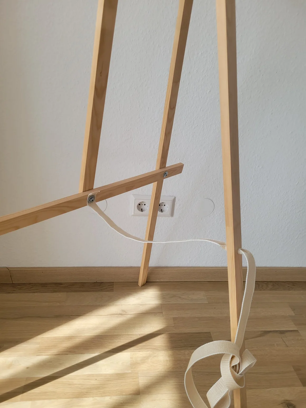 Der untere Teil einer hölzernen Staffelei auf einem Holzboden.