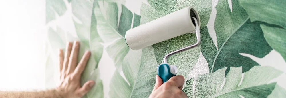 Person tapeziert Wand mit Mustertapete