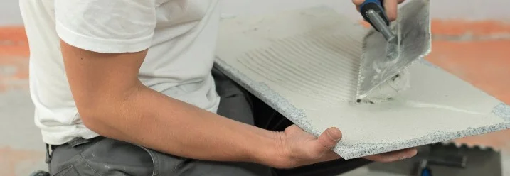 Person trägt Kleber auf Fliese auf