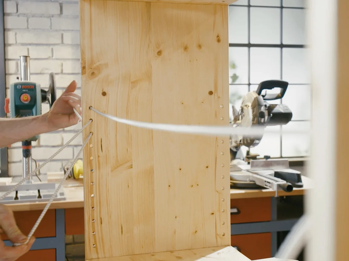 Person baut ein Holzregal zusammen