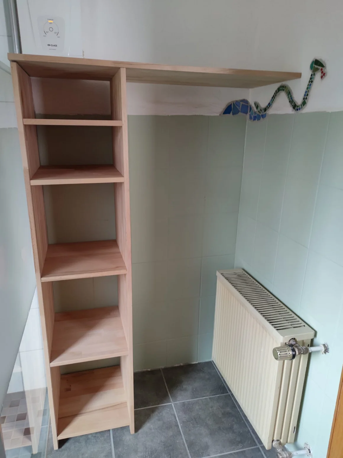 Selbstgebautes Holzregal mit Mosaik-Schlange in einem Badezimmer.