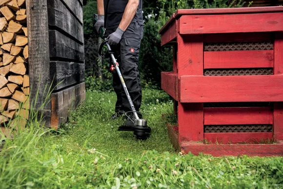 Person trimmt Rasen mit Rasentrimmer